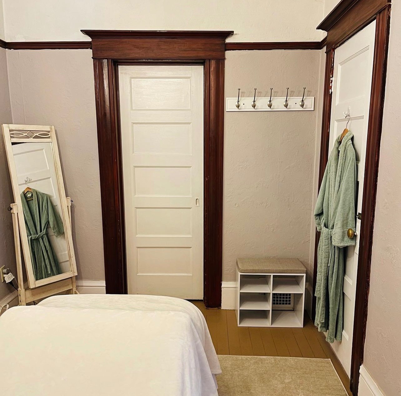 Treatment room with massage table, robe, and changing area